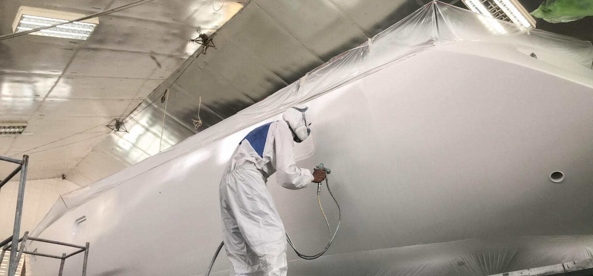 Worker spraying side of yacht